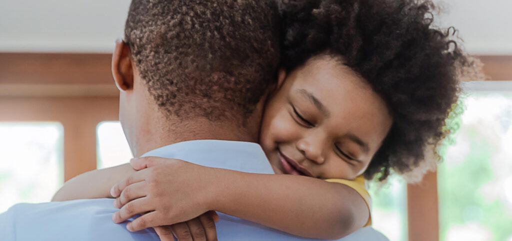 Portrait of father and son hugging in living room